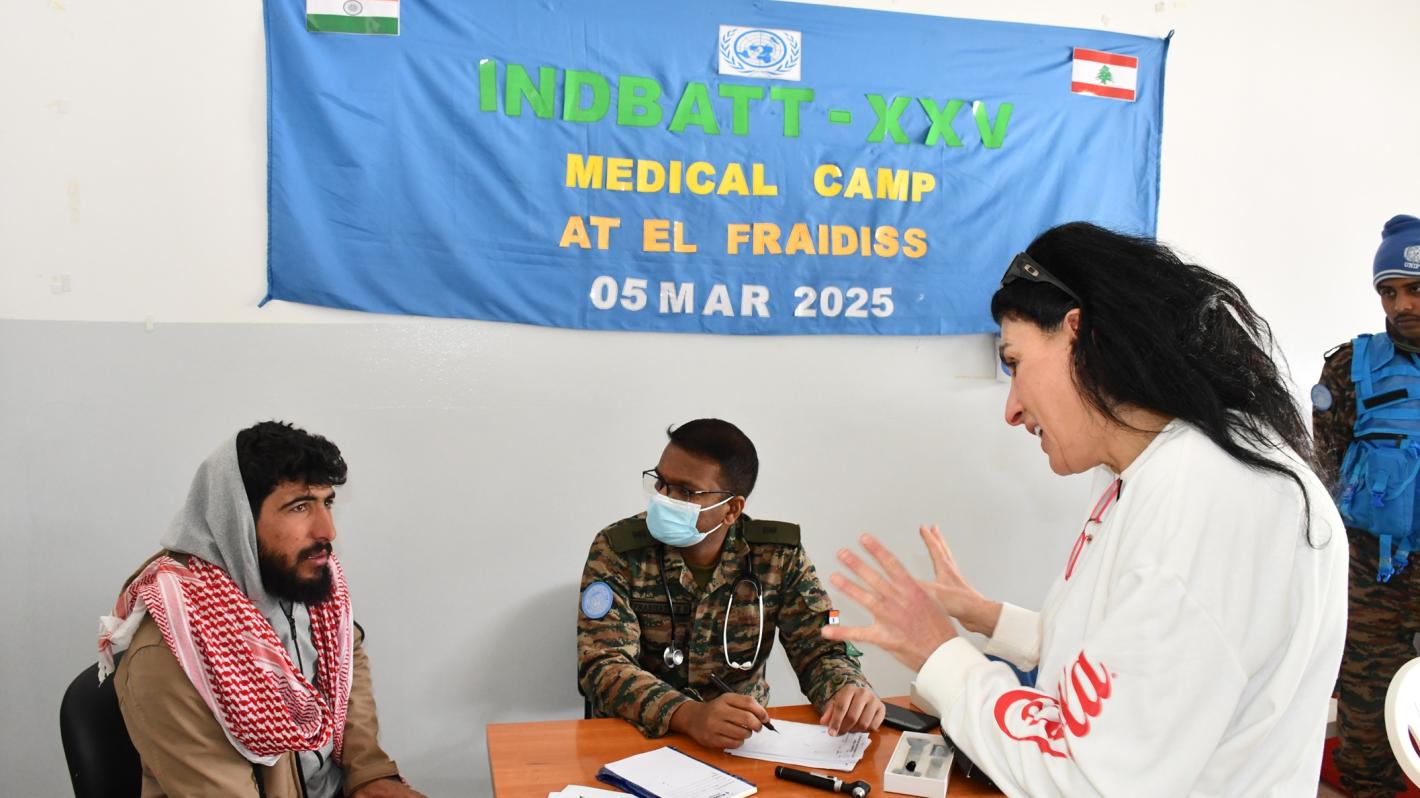 A woman explaining to a patient with a medical peacekeeper sitting next to the patient